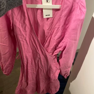 Rosa omlottklänning från Bik Bok - Säljer en söt rosa omlottklänning från Bik Bok. Klänningen har långa ärmar och en volangdetalj vid fållen. Perfekt för en färgglad look! 💖
