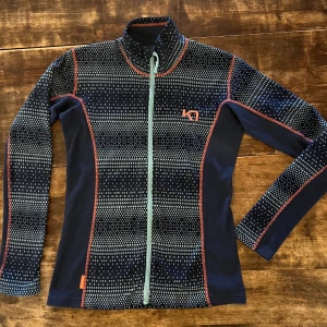 Mönstrad fleecetröja från Kari Traa - Säljer en snygg och funktionell tröja i microfleece från Kari Traa i storlek M-S. Tröjan är mörkblå med ett unikt mönster i ljusare nyanser och en turkos dragkedja. Tröjan är i mycket gott skick. Perfekt mellanlager skidbacken, vandringen eller kyliga dagar med sin mjuka och varma fleece.