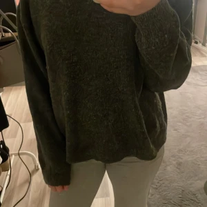 Grå  tröja - Säljer en mysig mörkgrön tröja med långa ärmar. Perfekt för kyligare dagar och enkel att matcha med olika outfits. Tröjan har en normal passform och är tillverkad i ett mjukt material. 