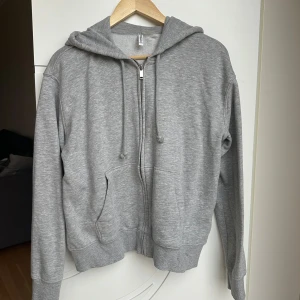 Grå hoodie från H&M - Säljer en basic grå hoodie från H&M Divided med dragkedja och huva. Den har långa ärmar och är mjuk på insidan. Använd fåtal gånger🙂