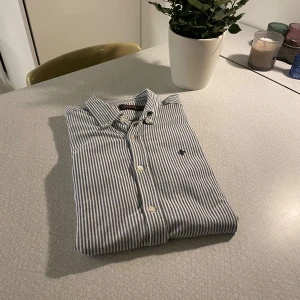 Randig skjorta från Morris - Snygg randig skjorta från Morris i blått och vitt. Skjortan har långa ärmar och knappar framtill. Perfekt för en stilren look och varmare väder. Bär den under en halfzip eller ovanpå en t-shirt, passag lika bra vilket som. Nypris 1400 kr!!! Bara att skriva ifall ni har frågor! 