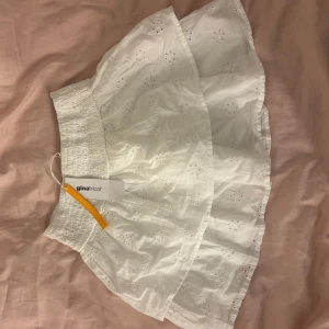 Vit kjol från Gina Tricot - Söt vit kjol från Gina Tricot med broderade detaljer och elastisk midja. Perfekt för varma dagar med sin luftiga design och charmiga volangkant. Storlek 134-140 men den sitter som en XS-S. Ett måste för garderoben!