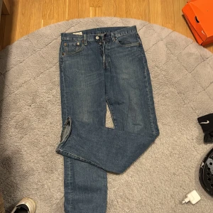 Blå jeans från Levi's - Snygga blå jeans från Levi's med klassisk femficksdesign och knappgylf. Perfekta för en avslappnad stil. De har en rak passform och är tillverkade i slitstarkt denim.