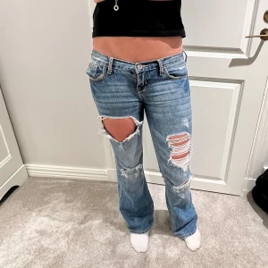 Blå jeans med slitningar från Hollister - Säljer mina hollister jeans i storlek 26! Jätte coola jeans med flera unika slitningar. Enda defekten är att det är lite slitningar på tyget där nere vid fållen!❣️❣️ midjemått: 38,5   innebernslängd:72