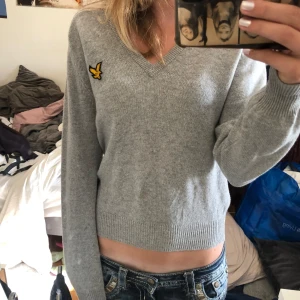 Lyle and scott tjocktröja med v neckline - Storlek S, vintage väldigt skön och varm! Ljus grå med en v neckline! Inte helt säker på materialet men iaf delvis ull. Var inte rädd att höra av dig och använd gärna köp nu☺️ Helt perfekt skick! (Den är inte cropped men har lågamidjade jeans)