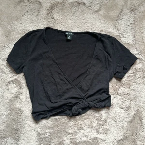Svart topp - Kortare topp, omlott med knytning. Skick 6/10