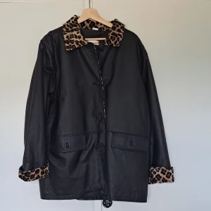Skinnjacka  - Skinnjacka med leopardmönstrad krage och ärmar.  Riktigt läder mycket sparsamt använd, och stor i storleken. 