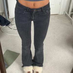 Svarta bootcut jeans - Säljer ett par snygga svarta bootcut jeans. De är lågmidjade och är lite slitna precis där man går vid hälarna, skriv för bild, annars bra skick!
