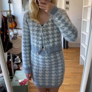 Mönstrat set i blått och vitt - Säljer ett supermysigt och fluffigt set från Fashion Nova. Det är i en härlig blå och vit färg med ett snyggt mönster. Koftan har långa ärmar och knäpps med pärlknappar framtill. Både kjolen och koftan kan säljas för sig själv, skicka till mig om ni bara vill ha en av dem! Koftan är i nyskick och kjolen i bra skick men har några trådar som sticker ut, inget som stör funktionen.
