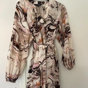 KLÄNNING - Söt klänning i fina färger, helt oanvänd. Skärpet är löst/ kan användas med eller utan. Mini längd. 