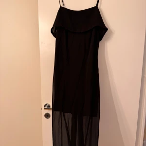 Svart klänning - Elegant svart klänning med transparent nederdel. Klänningen har smala axelband och en stilren design som passar perfekt för festliga tillfällen men även sena sommarkvällar! Klänningen är aldrig använd och är från H&M