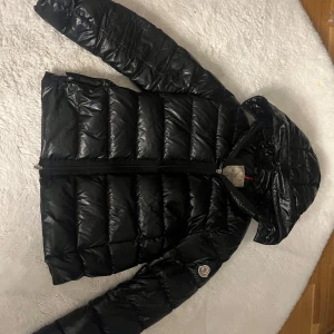 Moncler jacka - Snygg svart dunjacka från Moncler. den är väl använd och har haft den ca 1 år ändå. den har en pytte liten skada i höger armen längst ner. sedan är dragkedjan på ena fickan tyvärr sönder men inget som stör direkt. (sista bilden är hur den ska se ut) övrigt är den super fin nypris på 17k sänker såklart priset rätt ordentligt pga skador. kontakta mig vid frågor eller vid köp. storlek 2 (M) men passar som S. priset går att diskutera.