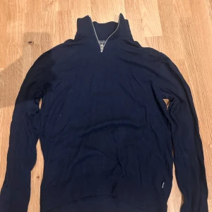 Mörkblå tröja med dragkedja från Jack & Jones - Snygg mörkblå tröja från Jack & Jones med halv dragkedja och hög krage. Perfekt för kyligare dagar och enkel att matcha med olika outfits. Storlek är M men passar även som S.