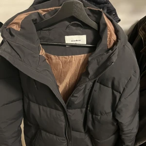 Svart pufferjacka från Woodbird - Säljer en svart pufferjacka från Woodbird i storlek M. Jackan är väldigt bra att ha till vardags vid dem kalla dagarna men funkar även väldigt bra till skidbacken. Nypris ca 2500