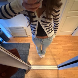 Randig kofta med knappar - Säljer en stilren randig kofta i svart och vit med knappar framtill. Koftan har långa ärmar och en klassisk design som passar perfekt för en avslappnad look.