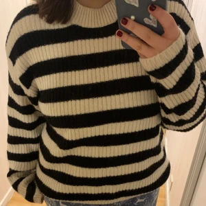 Randig stickad tröja - Säljer en mysig randig tröja från H&M i svart och beige. Tröjan är stickad med långa ärmar och har en rund halsringning. Perfekt för kyliga dagar! Har haft på mig den en gång och den tvättades efter.