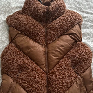 Brun teddyjacka med dragkedja - Säljer en mysig brun teddyjacka med dragkedja. Jackan har en pufferdesign med teddyfoder som ger extra värme och stil. Perfekt för kyliga dagar! Storlek 38, passar 36&34. Helt oanvänd