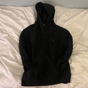 Ralph Lauren hoodie - Säljer en klassisk svart hoodie från Ralph Lauren med en liten röd logga på bröstet. Perfekt för en avslappnad stil med en bekväm passform och huva. Den är i storlek XL för barn vilket motsvarar S. 