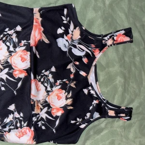 Svart blommig klänning  - Snygg svart klänning med blommigt mönster i rosa och vita nyanser. 