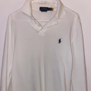 Vit pikétröja | Ralph Lauren - Klassisk vit pikétröja från Ralph Lauren med den ikoniska loggan broderad i blått på bröstet. Max använd 2 gånger, passar perfekt på 160-178 cm. Tveka ej kontakta vid frågor😅