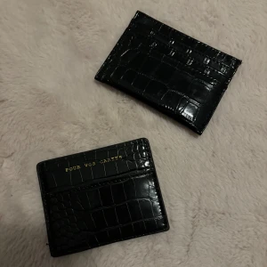 Svart krokodilpräglad plånbok - Snygg svart plånbok med krokodilpräglat mönster och texten 'POUR VOS CARTES' i guld. Perfekt för att hålla dina kort organiserade med stil. Båda för 80kr
