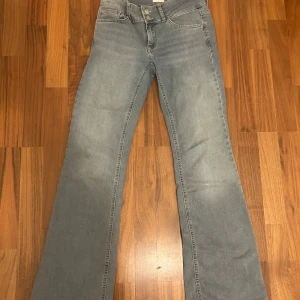 Ljusblå bootcut jeans från Nelly - Snygga ljusblå bootcut jeans från Nelly med hög midja och dubbla knappar. Perfekta för en avslappnad stil med en touch av retro. Original priset för den är 699kr. 