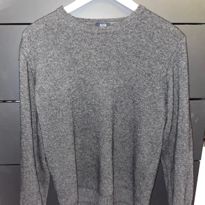 Grå stickad tröja från Sir of Sweden - Snygg och stilren grå stickad tröja från Sir of Sweden. Perfekt för kyligare dagar med sin mjuka och bekväma passform. Svart ull tröja köpt för 1300kr.