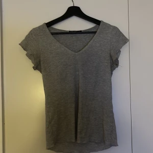 Grå t-shirt från Giovanny - Säljer en stilren grå t-shirt från Giovanny i storlek S. T-shirten har en v-ringad hals och korta ärmar, perfekt för en avslappnad look. Materialet är mjukt och bekvämt.