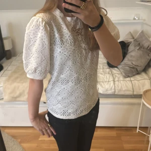Vit spetsblus med puffärmar - Säljer en söt vit spetsblus med puffiga kortärmar. Blusen har ett vackert broderat mönster och en rund halsringning. Perfekt för en somrig look!💓