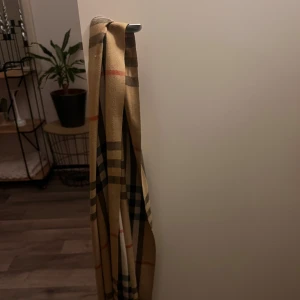 Rutig halsduk - Snygg rutig halsduk i beige, svart och röd. Perfekt för att ge en klassisk touch till din outfit. Passar bra till kyligare dagar.