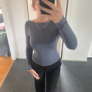 Grå långärmad topp med öppen rygg - Snygg gblå långärmad topp med en stilren design och öppen rygg.