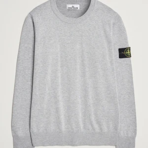 Stone Island Sweatshirt - Snygg grå tröja från Stone Island med rund hals och ribbade muddar. Tröjan har en ikonisk logga på ärmen som ger en stilren touch. Perfekt för en avslappnad och trendig look. Skriv för bilder osv! 