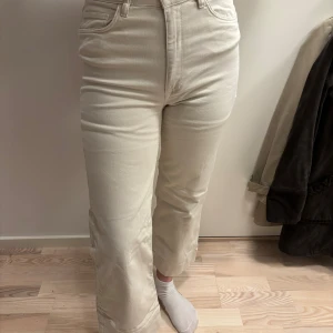 Beige jeansbyxor - Snygga beige jeansbyxor med hög midja och rak passform. Perfekta för en stilren look. Klassisk design med fem fickor och knappgylf. Lite blandning av bootcut och straight leg