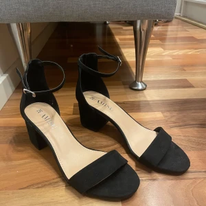 Svarta klackskor från Amisu - Snygga svarta klackskor från New yorker med öppen tå och justerbart spänne runt ankeln. Perfekta för en elegant look med bekväm blockklack. Tyvärr fel storlek för mig så aldrig använda!