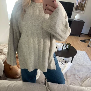 Beige stickad tröja - Mysig beige stickad tröja med en loose passform, slits och långa ärmar. ger en avslappnad look. Passar bra till jeans eller leggings.