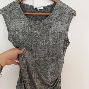 Silvrig topp från Calvin Klein - Snygg festtopp från Calvin Klein, silvrig och sitter figursytt.