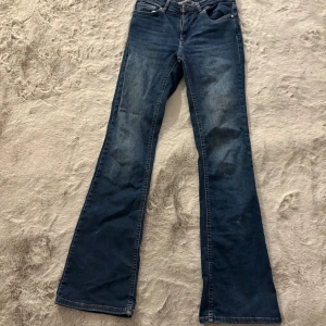 Blå bootcut jeans - Snygga blå bootcut jeans med klassisk femficksdesign. Perfekta för en avslappnad stil med en touch av retro. De har en bekväm passform.