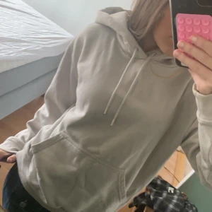 Beige/grå hoodie från H&M - Säljer en hoodie från H&M i storlek XS. Den har en klassisk design med ficka och justerbar huva.