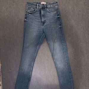 Blå jeans från Zara - Snygga blå jeans från Zara med en klassisk femficksdesign och knappgylf. De har en smal passform och är perfekta för en stilren look. Tillverkade i ett slitstarkt denimtyg.