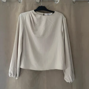 Beige blus från Zara - Elegant beige blus från Zara med långa ärmar och rund hals. Helt oanvänd! 