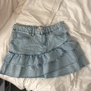 Volang jeanskjol - Från Ginatricot, knappast använd💕Säljer då den inte riktigt är min stil. Strl 36, passar mig som är 176 cm. Midjemått: 38 cm, längd: 40 cm