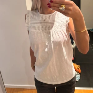 Vit ärmlös blus från Esprit - Säljer en söt vit blus från Esprit med fina detaljer. Blusen är ärmlös med volangdetaljer vid axlarna och har ett vackert mönster. Superfin! Men kommer inte till användning