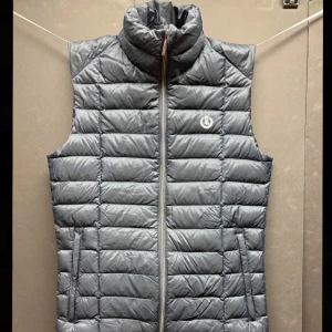 Mörkblå quiltad dunväst från Henri Lloyd - Säljer denna feta Henri Lloyd väst som har använts flitigt, men är ändå i bra skick. Perfekt inför våren och är väldigt trendig. Nypris på en sån här är runt 1599KR. Passar med allt.              Lite defekt med ett väldigt litet hål men som inte syns vid användning!🫡