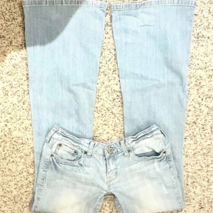 Ljusblå jeans med vida ben - Snygga ljusblå jeans med vida ben och klassisk femficksdesign. De har en knappgylf och dekorativa sömmar på bakfickorna. Perfekta för en avslappnad stil. Midjemått=ca37cm. Innerbenslängd=80cm