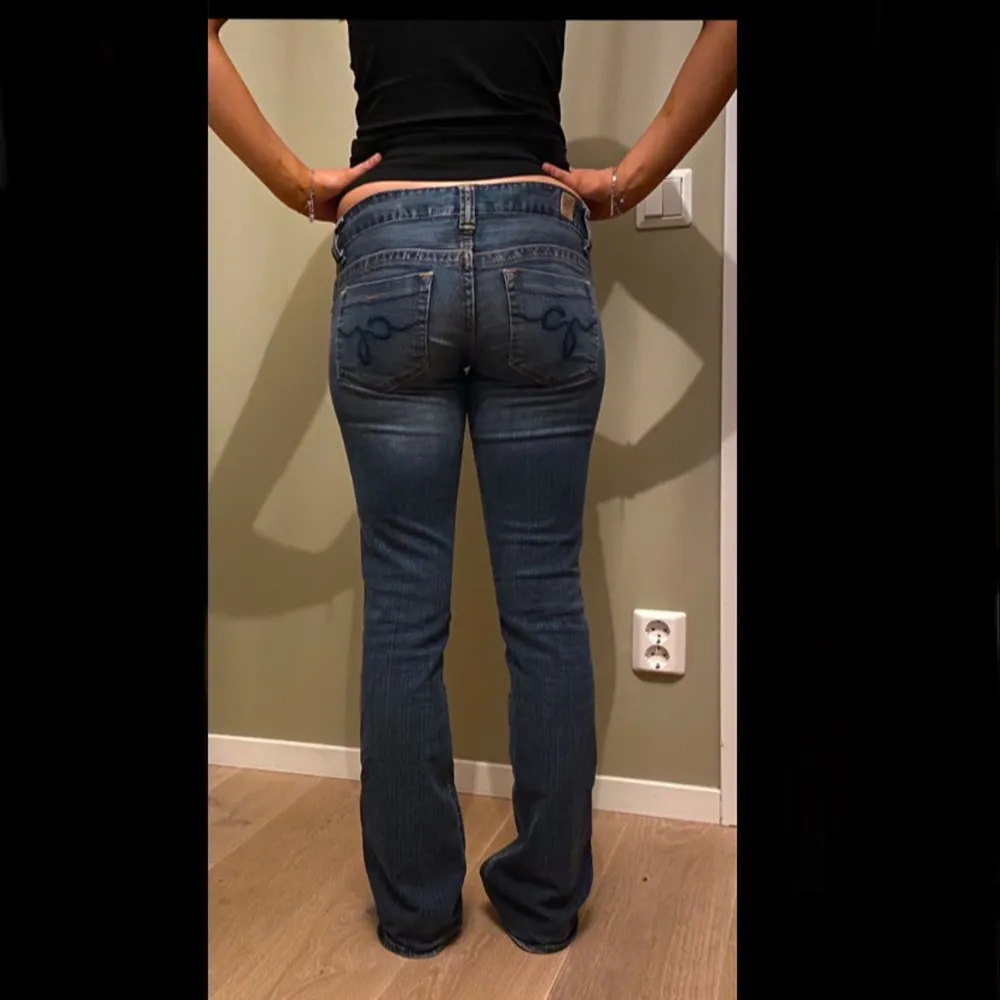 Säljer ett par snygga blå low waist bootcut jeans från Guess. De har en super gullig ficksdesign. Inerbenslängden: 82cm, midja: 39 cm rakt över🩷 Det är ett snöre i midjan på insidan pågrund av att dom är för stora för mig i midjan.( Se bild 4 ) snöret synns inte utåt och kan tas ut! skriv vid frågor!💕. Farkut & Housut.