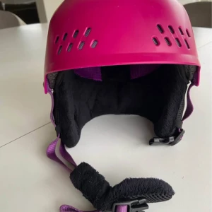 Rosa hjälm från K2 - Snygg rosa hjälm från K2 med ventilationshål och justerbart hakband. Hjälmen har en dekorativ logotyp på sidan och är vadderad för extra komfort. Perfekt för vintersport!