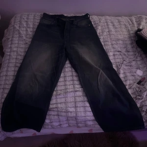 Medium wash baggy jeans - Snygga medium baggy jeansbyxor med en loose passform. De har en klassisk design med fyra fickor och knappgylf. Perfekta för en avslappnad stil.