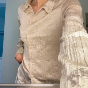 Beige blus/skjorta från Monki - Helt ny beige blus/skjorta från Monki med ett krinklat mönster och klassisk krage. Blusen har långa ärmar och knappar. 