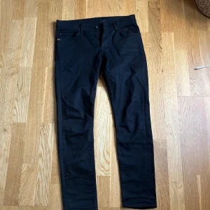 Svarta byxor från Tiger of Sweden - Säljer dessa feta svarta jeans från Tiger of Sweden i nyskick då de är för korta för mig. De är använda ett fåtal gånger men inte mer än så. Sorleken är 31/32. Pris kan diskuteras.