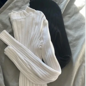 Vit och svart ribbade polotröjor - Säljer två snygga ribbade magtröjor i vit och svart. Finns en liten fläck på den vita tröjan.